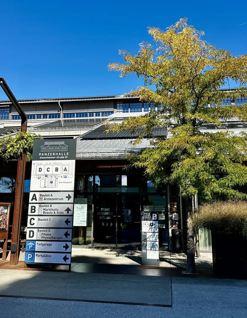 Eingang B der Panzerhalle in Salzburg mit Wegweiser zu Bauteil B, Markthalle und Beauty & Style